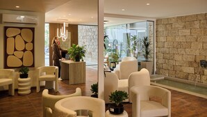 A modern lobby with a reception desk, seating area, and a stone wall. - Zeus Piraeus Grand (Piraeus)