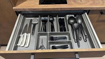 Eine Schublade mit ordentlich angeordneten Küchenutensilien, darunter Messer, Gabeln, Löffel und eine Schere.