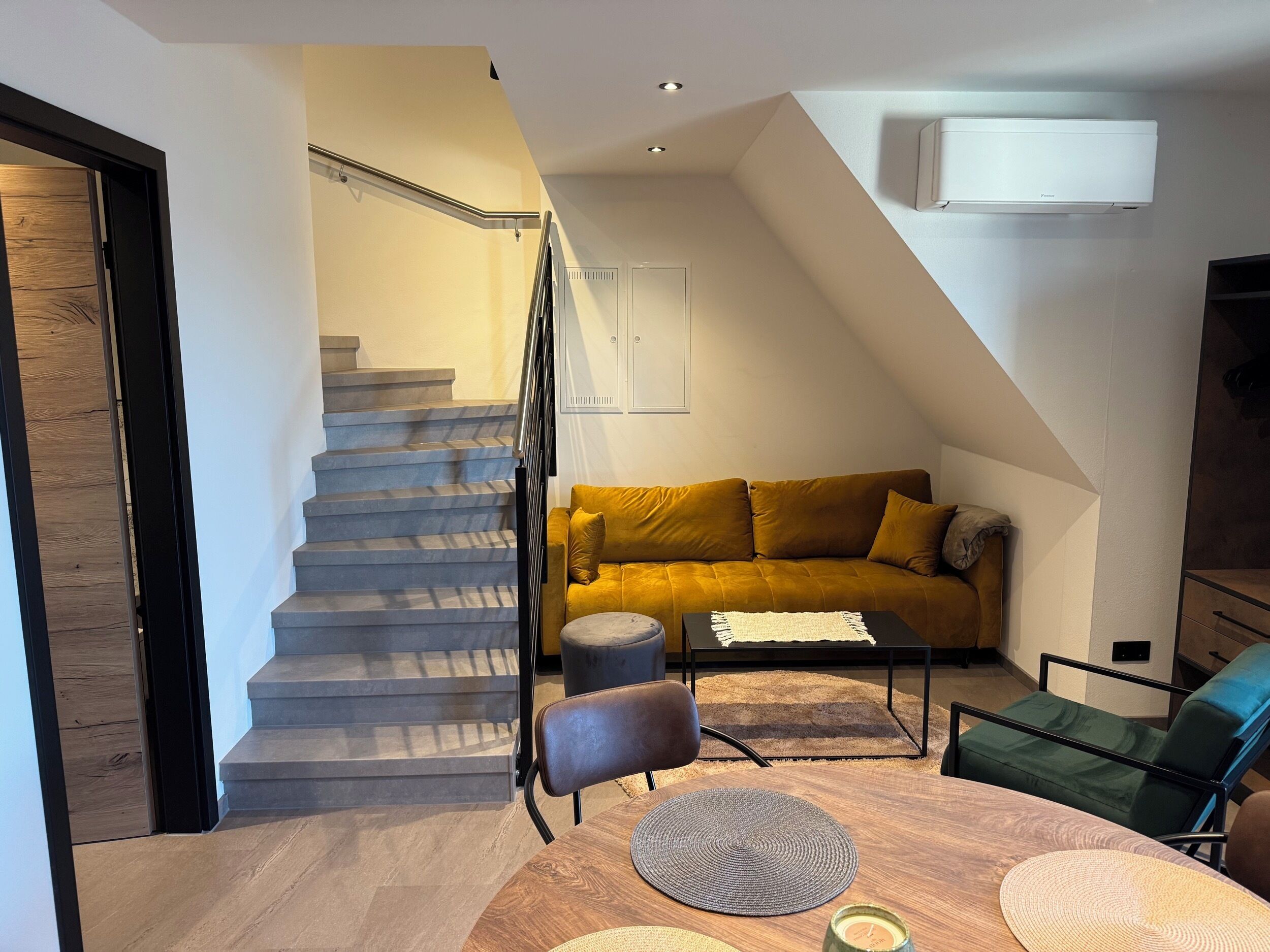 Un espace de vie moderne comprenant un escalier, un canapé, une table basse et une table à manger.