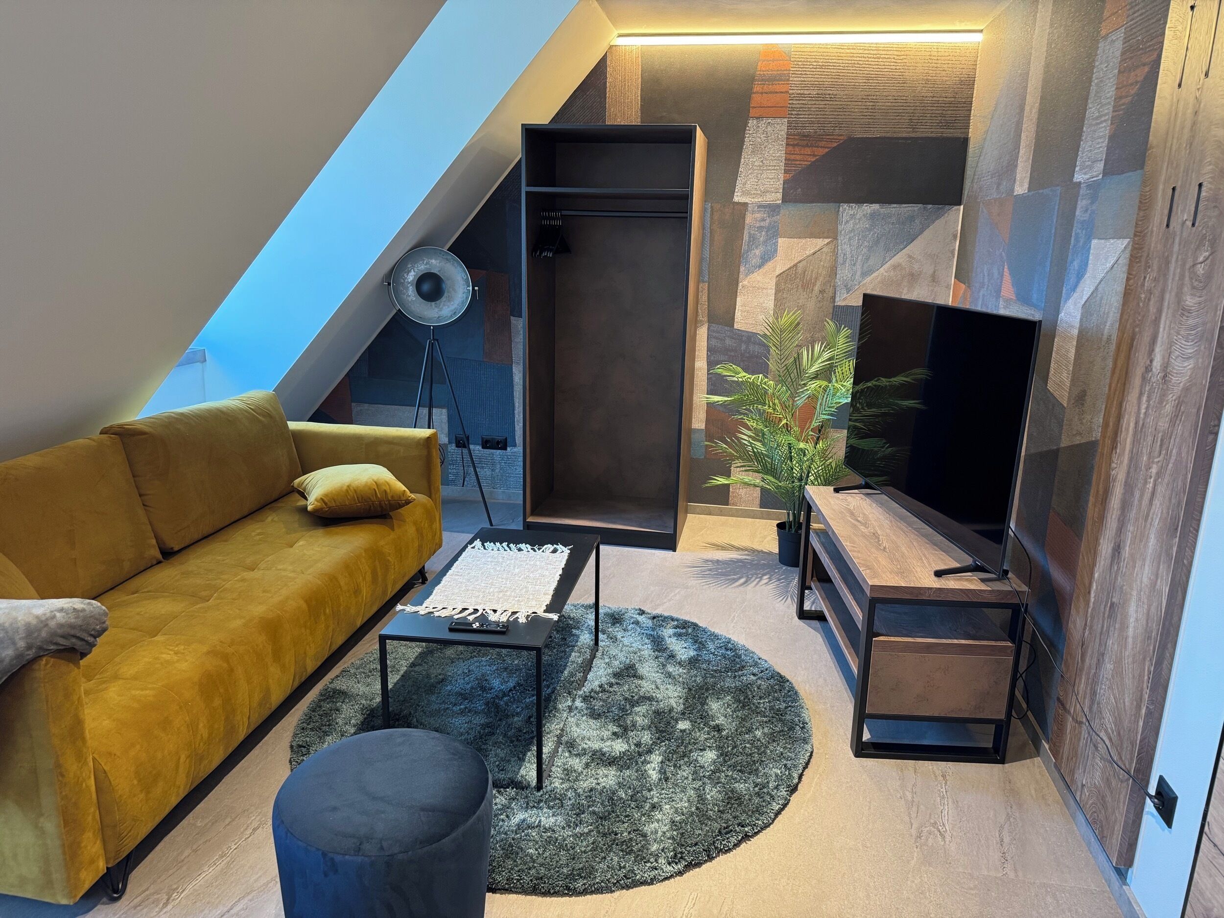 Una sala de estar moderna estilo loft con un sofá, una mesa de centro, un mueble para televisión y una lámpara de pie.