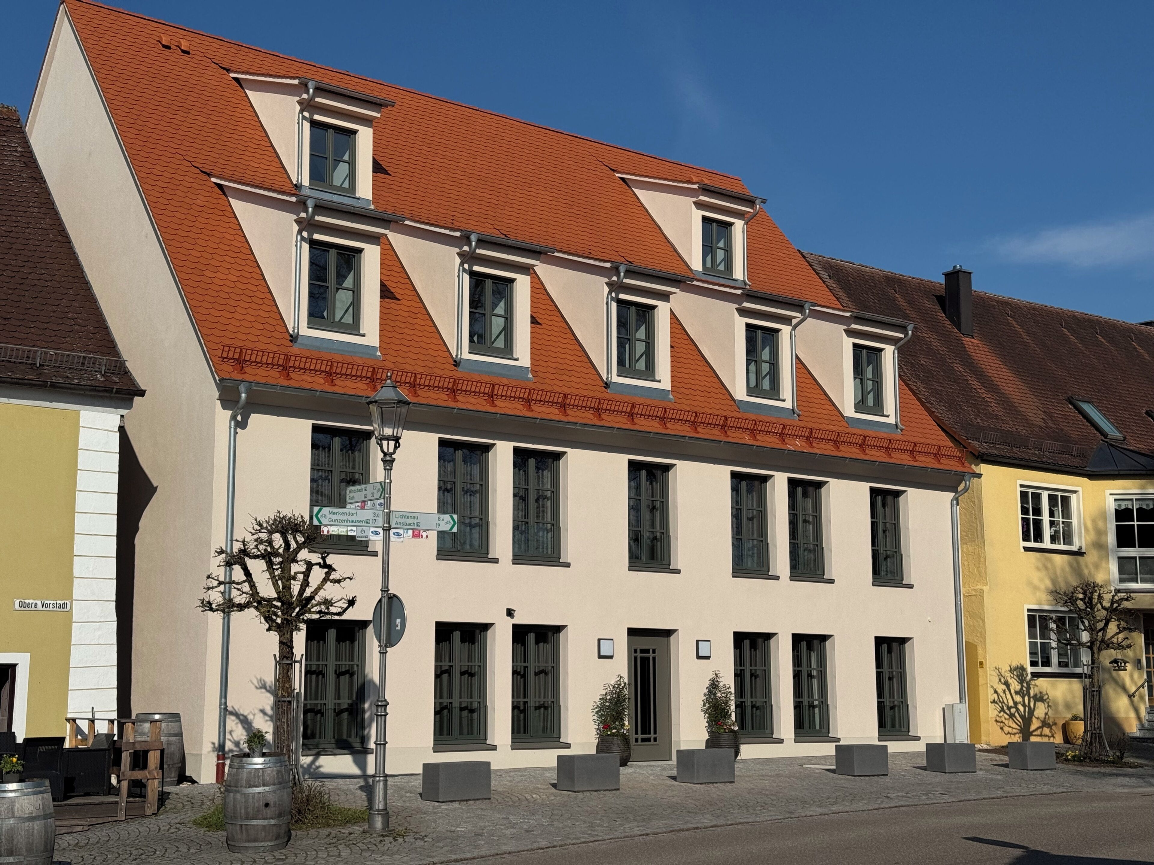 A building with a sloped roof, multiple windows, and a street in front.