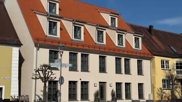 A building with a sloped roof, multiple windows, and a street in front.