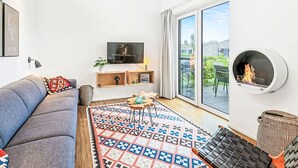 Una sala de estar moderna con un sofá, televisión, chimenea y un ventanal grande.