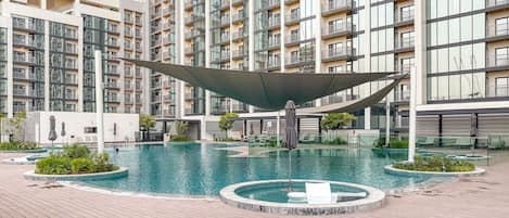 A modern residential building with a swimming pool and a covered area.