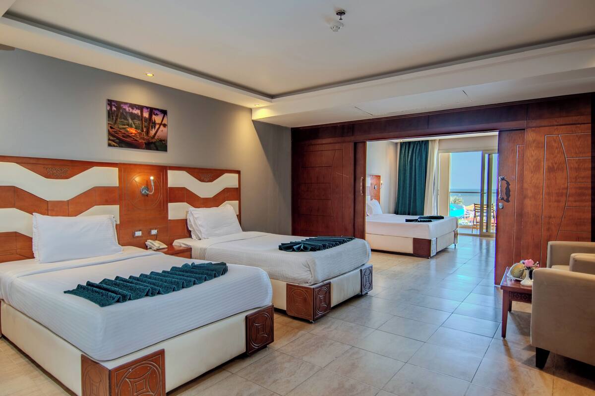 A hotel room with two beds, a large window, and a view of the outdoors.
