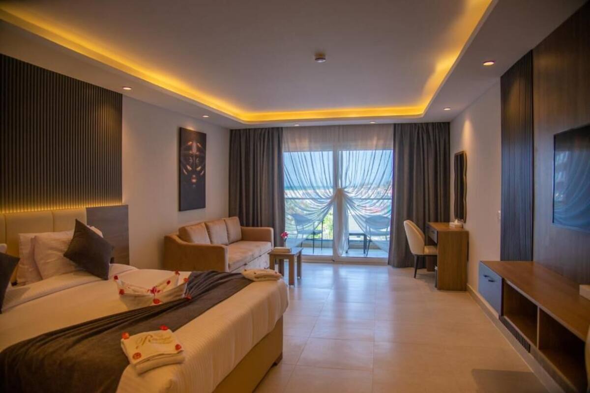 A modern hotel room with a large bed, a desk, a chair, and a TV.