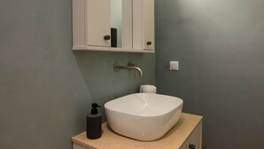 Ein Badezimmer mit einem weißen Waschtank, einem Handtuchspender und einem Spiegel über dem Waschbecken.