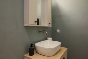Ein Badezimmer mit einem weißen Waschtank, einem Handtuchspender und einem Spiegel über dem Waschbecken.
