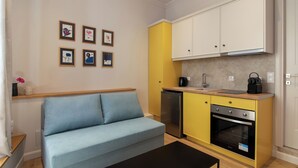 Ein kompakter Wohnbereich mit Sofa, Küchenzeile und Wandbild.