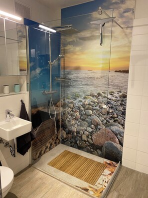 A bathroom with a glass shower enclosure, a sink, and a toilet.