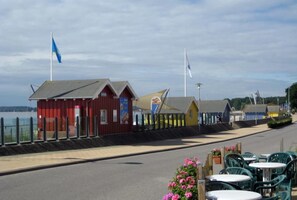 A pier with red and yellow buildings, a flag, and outdoor seating.