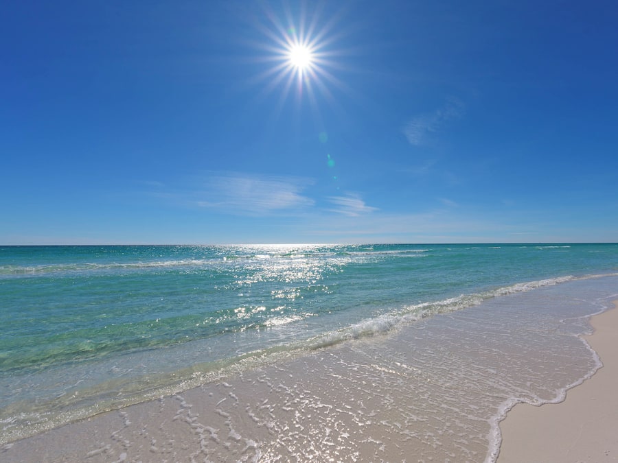 A beach with clear blue water and a bright sun.