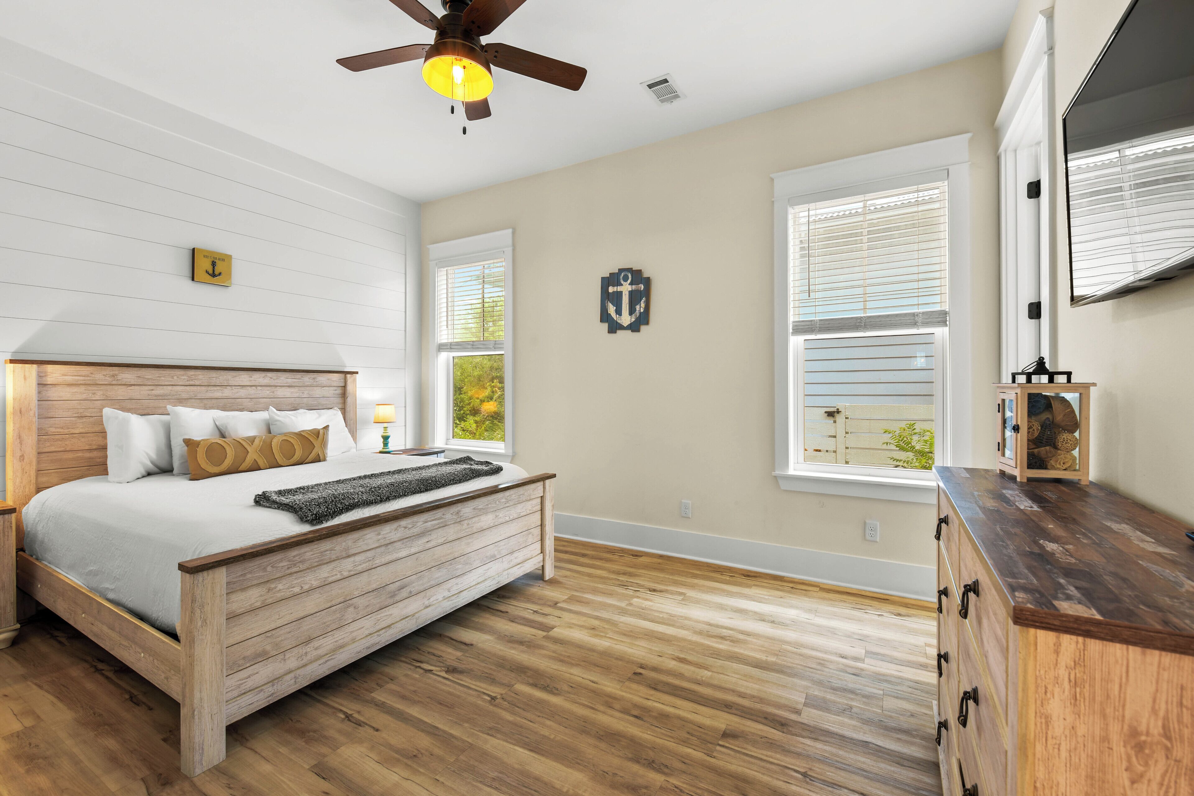 Un dormitorio con cama de madera, ventilador de techo y cómoda.