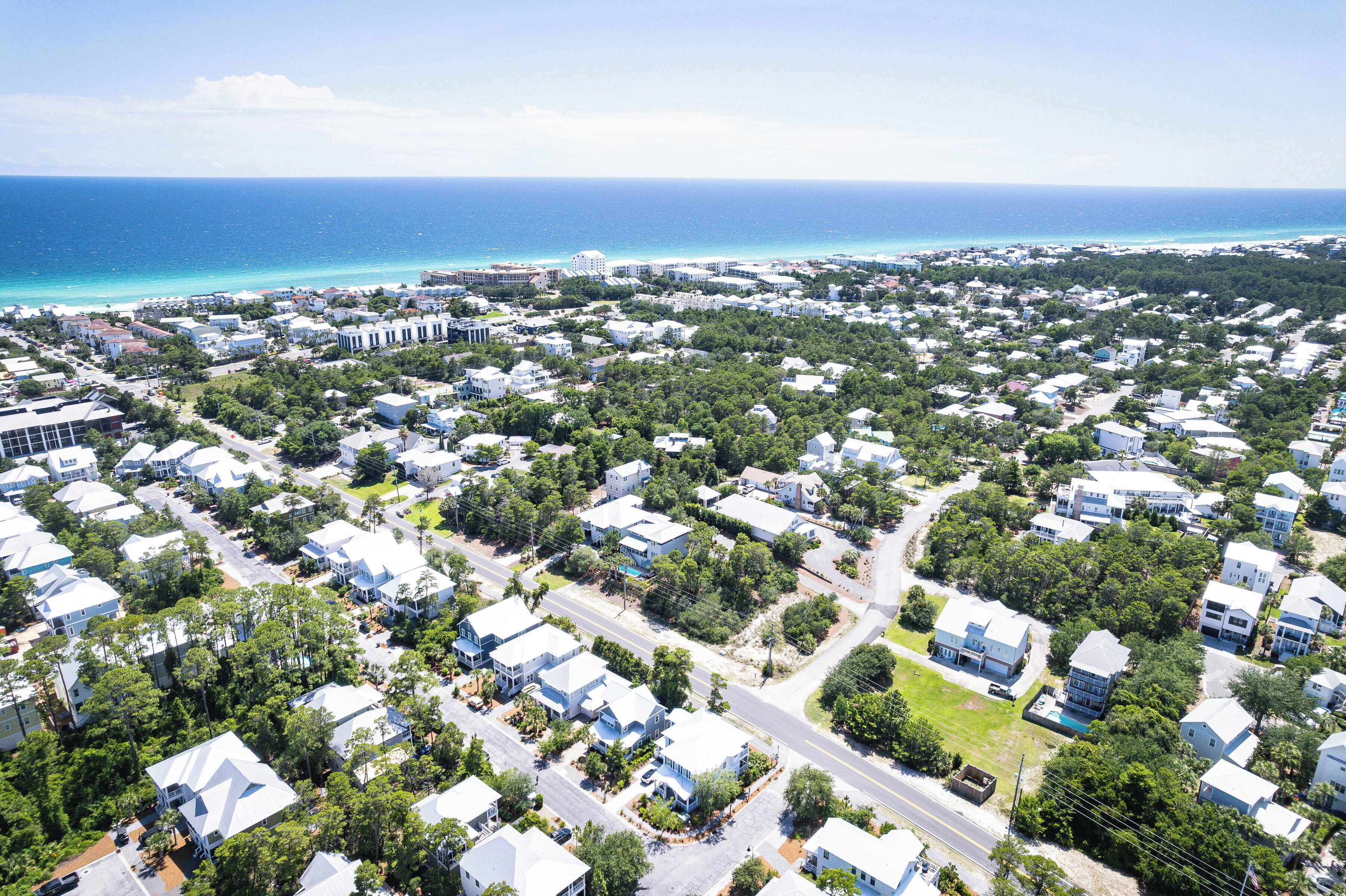 An aerial view of a coastal residential area with houses, roads, and a beach.