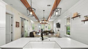 A modern kitchen with a central island, pendant lights, and a view to the dining area. - Retreat at 30A (Santa Rosa Beach)