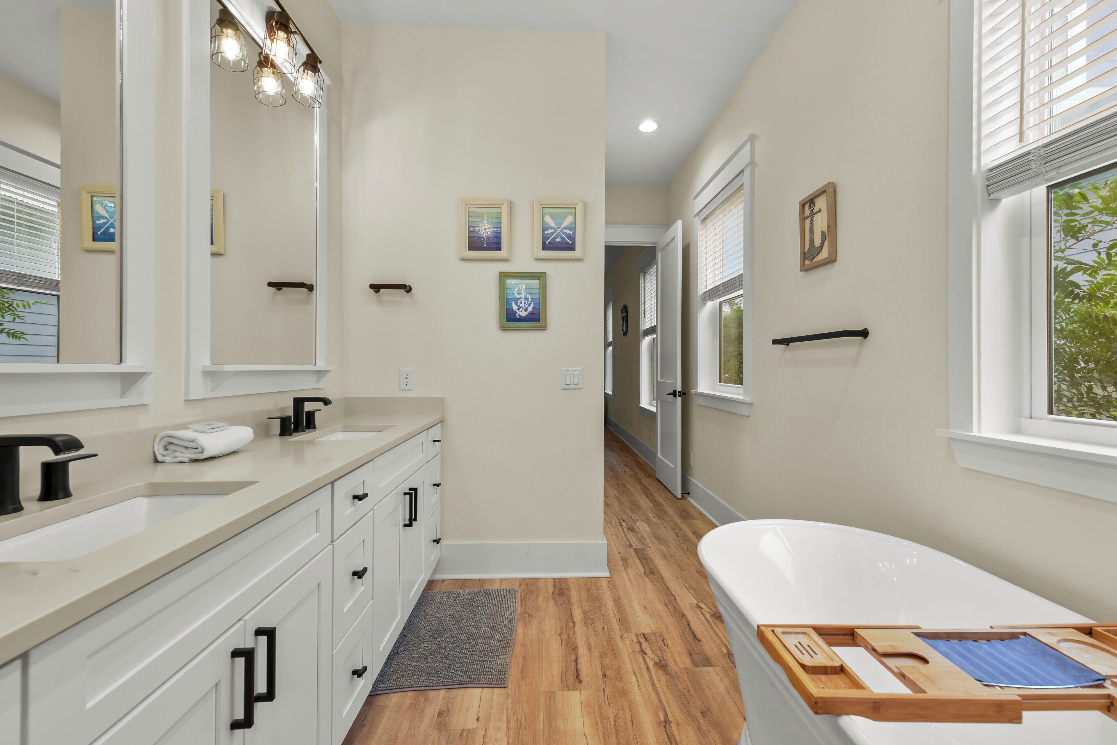 A modern bathroom with a large mirror, a bathtub, and a vanity with a sink and towel rack.