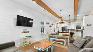 A spacious living room with a large TV, a wooden coffee table, and a sofa. - Retreat at 30A (Santa Rosa Beach)