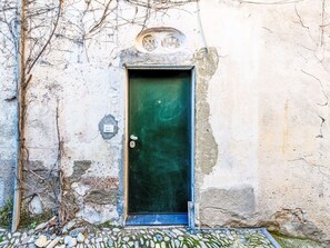 Ein verwittertes Gebäude mit einer grünen Tür, einem kleinen Fenster und einer Steinwand.