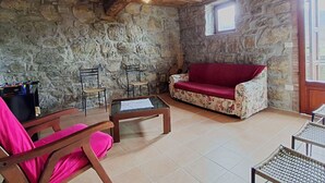 A rustic stone-walled room with a wooden ceiling, a red sofa, a wooden coffee table, and wicker chairs. - Beautiful private villa for 12 guests with private pool, WIFI, TV and pets allowed (Castel Di Casio)