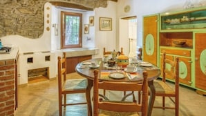A rustic dining area with a stone wall, wooden ceiling beams, and a green cabinet with clocks. - Beautiful private villa for 12 guests with private pool, WIFI, TV and pets allowed (Castel Di Casio)