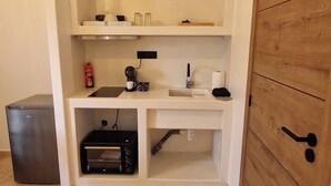 A compact kitchenette with a built-in oven, a coffee maker, and a sink. - Alya Paros – Calm Cycladic Aesthetic (Paroikia)