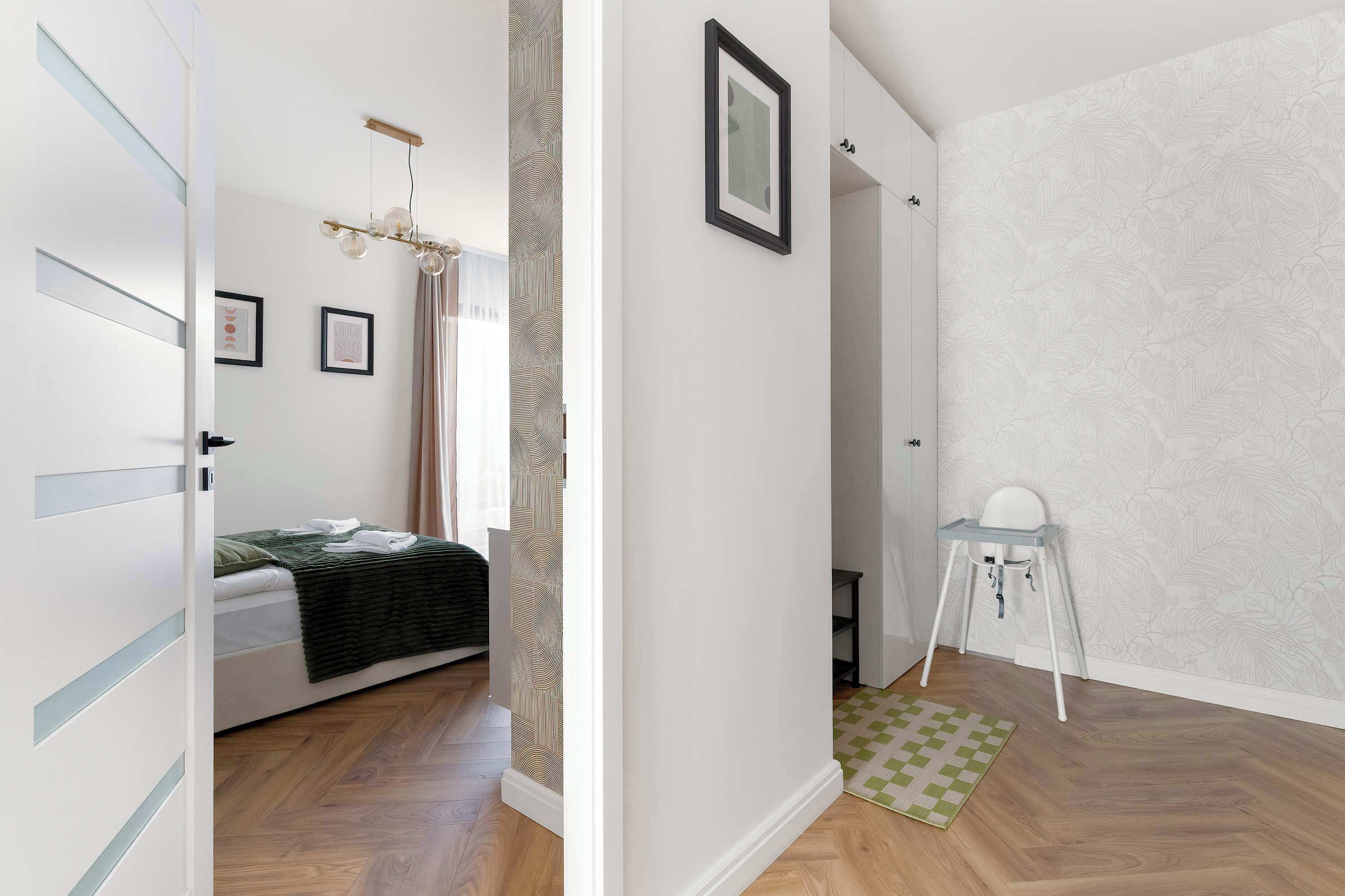 Ein Schlafzimmer mit Bett, Sessel, kleinem Tisch und einem Wandbild.