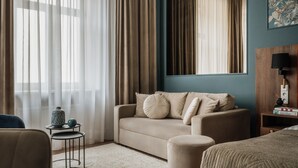 A hotel room with a sofa, a small side table, a lamp, and a bed. - White Lotus by Fragola Apartments (Kraków)