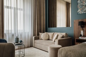 A hotel room with a sofa, a small side table, a lamp, and a bed. - White Lotus by Fragola Apartments (Kraków)