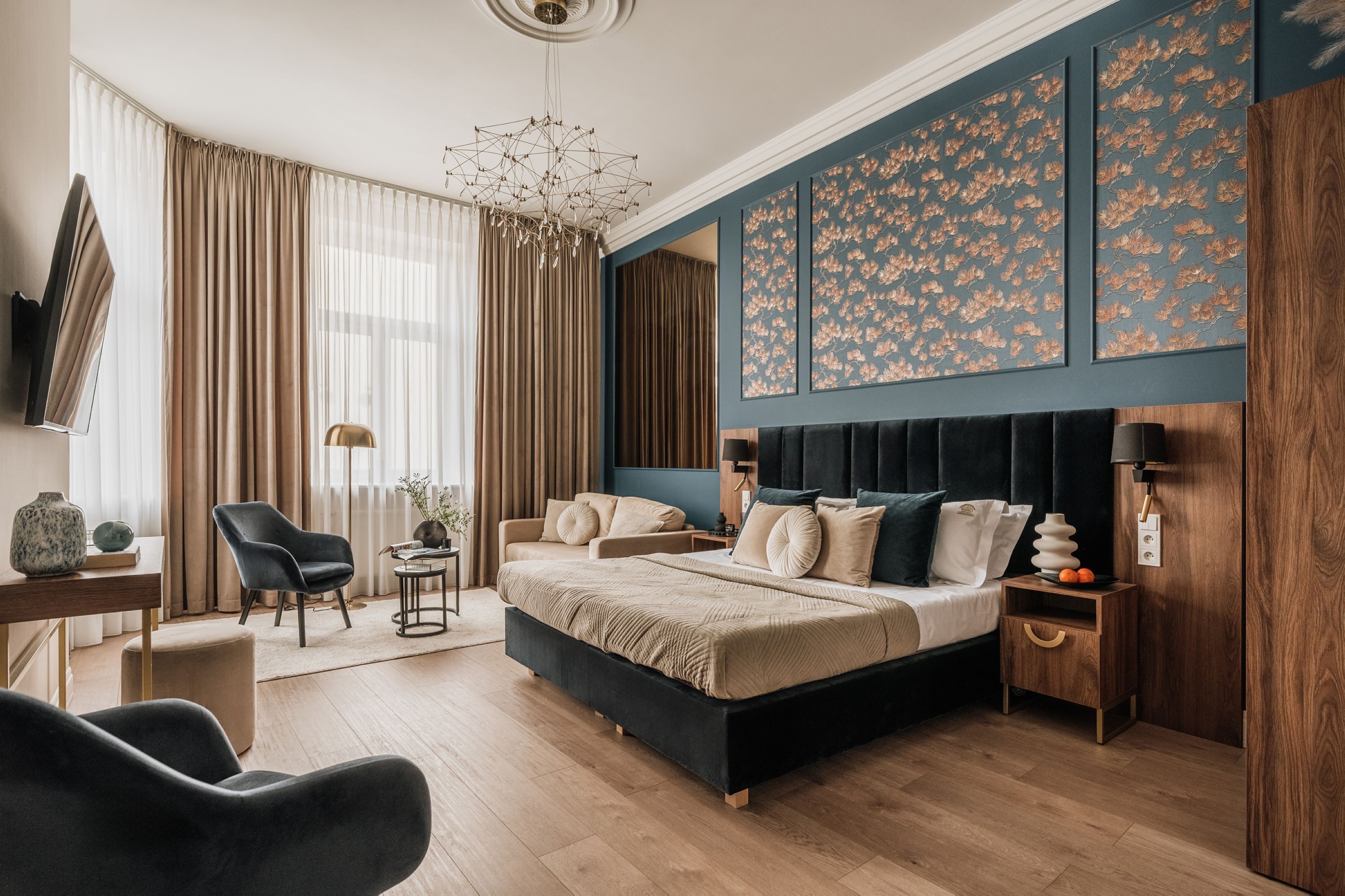 A modern bedroom with a large bed, a desk, a chair, and a TV.