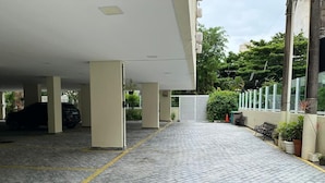 Un'area di parcheggio coperta con vialetto lastricato, colonne e piante in vaso.