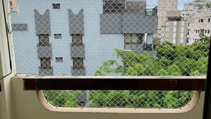 Un balcone con ringhiera in metallo, vista su edifici e pavimento piastrellato.