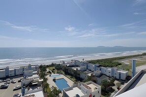 A coastal hotel with a swimming pool, beach view, and multiple buildings.