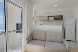 A modern living room with a sofa, a built-in microwave, and a refrigerator.
