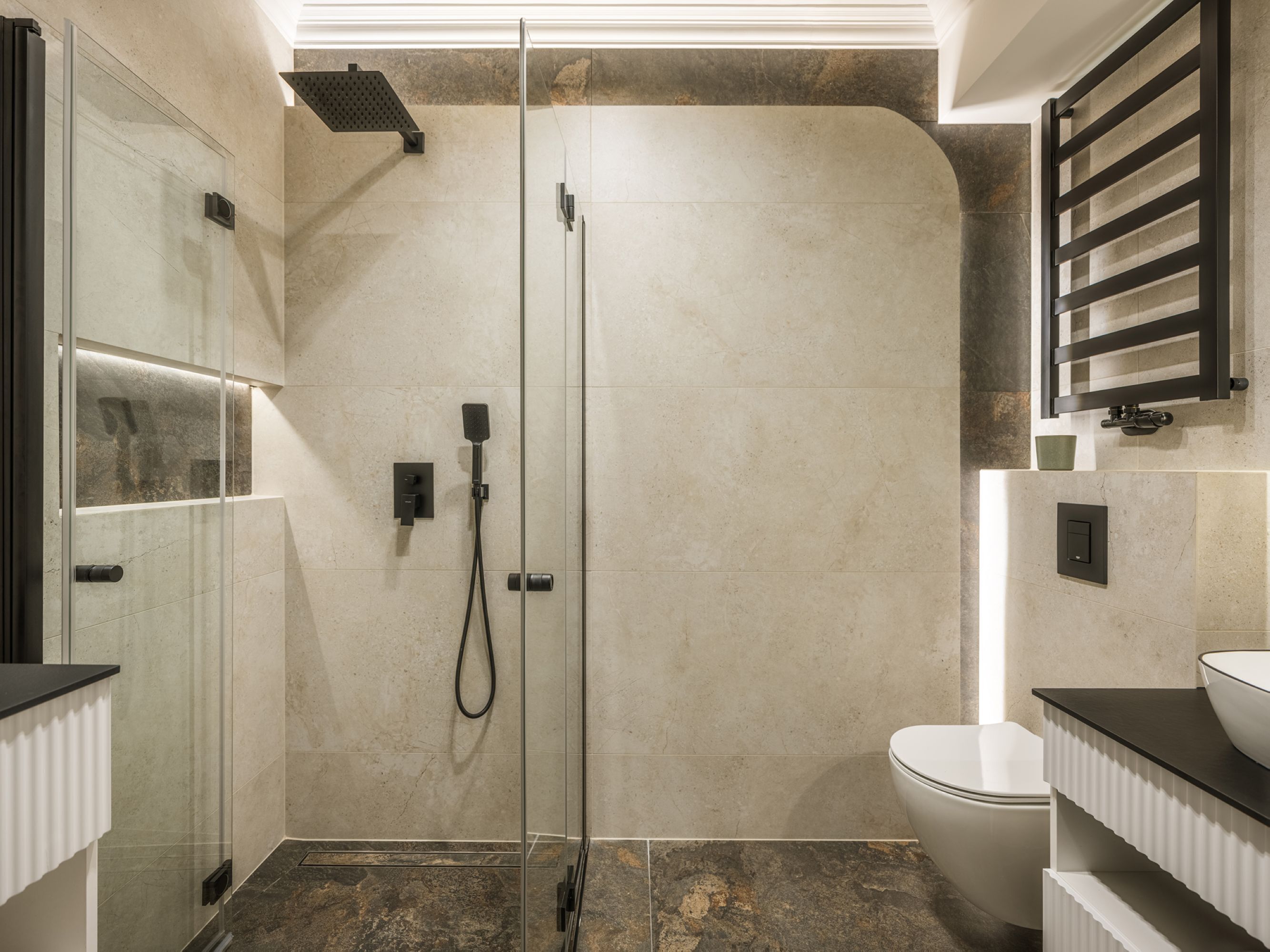 Un baño moderno con ducha de vidrio, inodoro y lavabo con encimera negra.