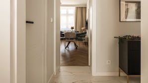 Un couloir mène à une salle à manger où se trouvent une table et des chaises, un radiateur et un tableau encadré accroché au mur.