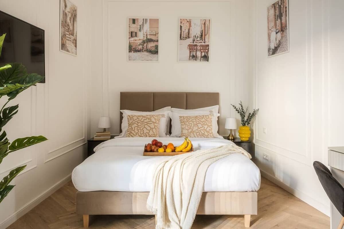 Een keurig opgemaakt slaapkamer met een bed, nachtkastjes en een mand met fruit.