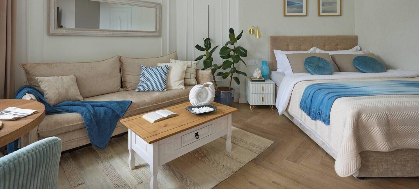 A bedroom with a bed, a sofa, a small table, and a nightstand.