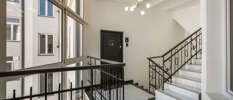 A modern interior with a staircase, a black door, and a security camera on the ceiling.