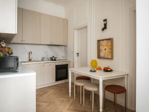 Eine kleine Küche mit weißen Schränken, einem weißen Esstisch und einem kleinen Backofen.