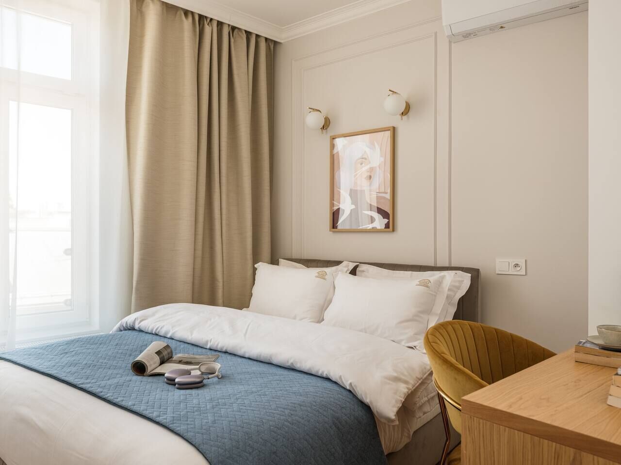 A hotel room with a bed, a desk, and a window with curtains.