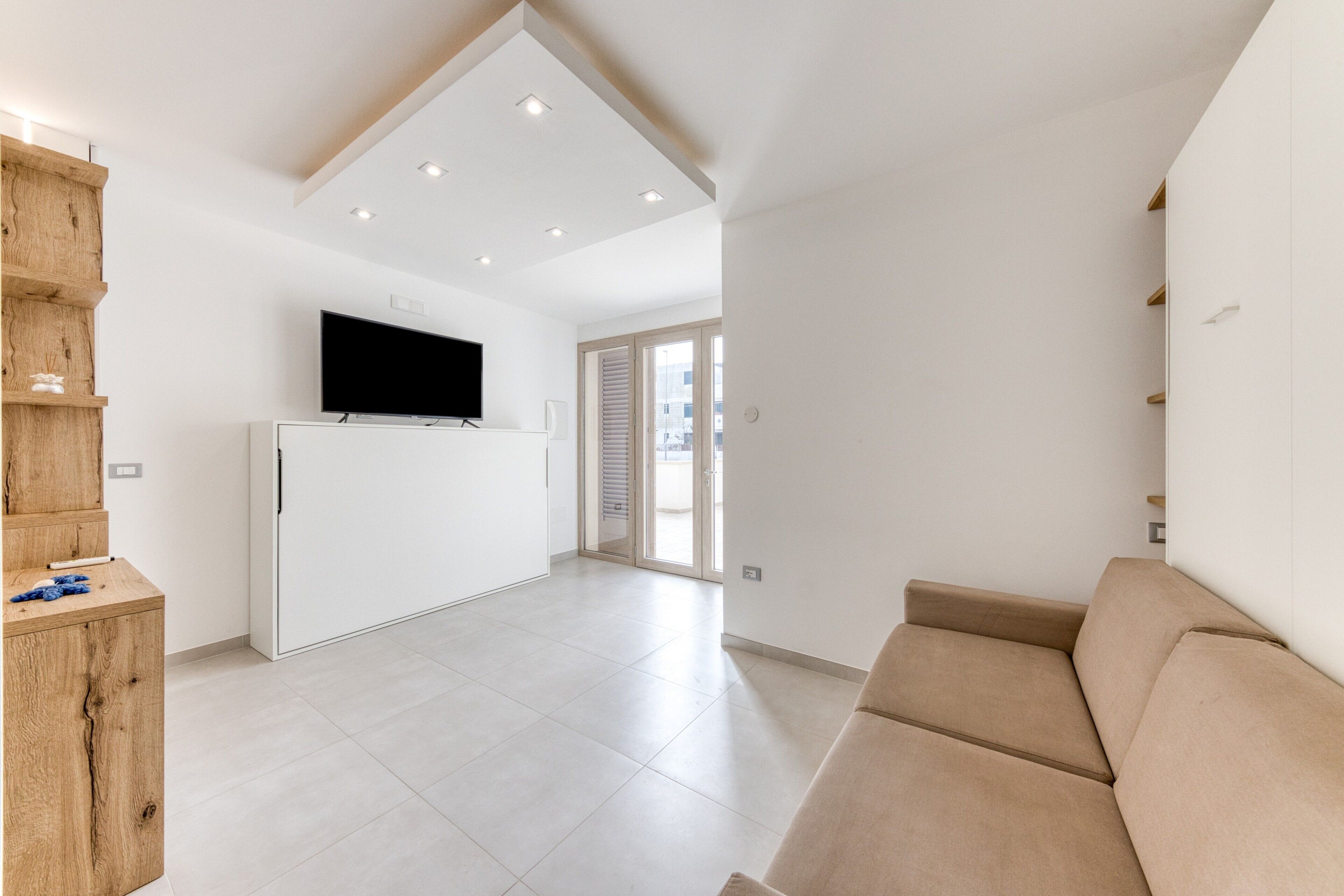 Een moderne woonkamer met een flatscreen televisie, een bank en een houten kast.