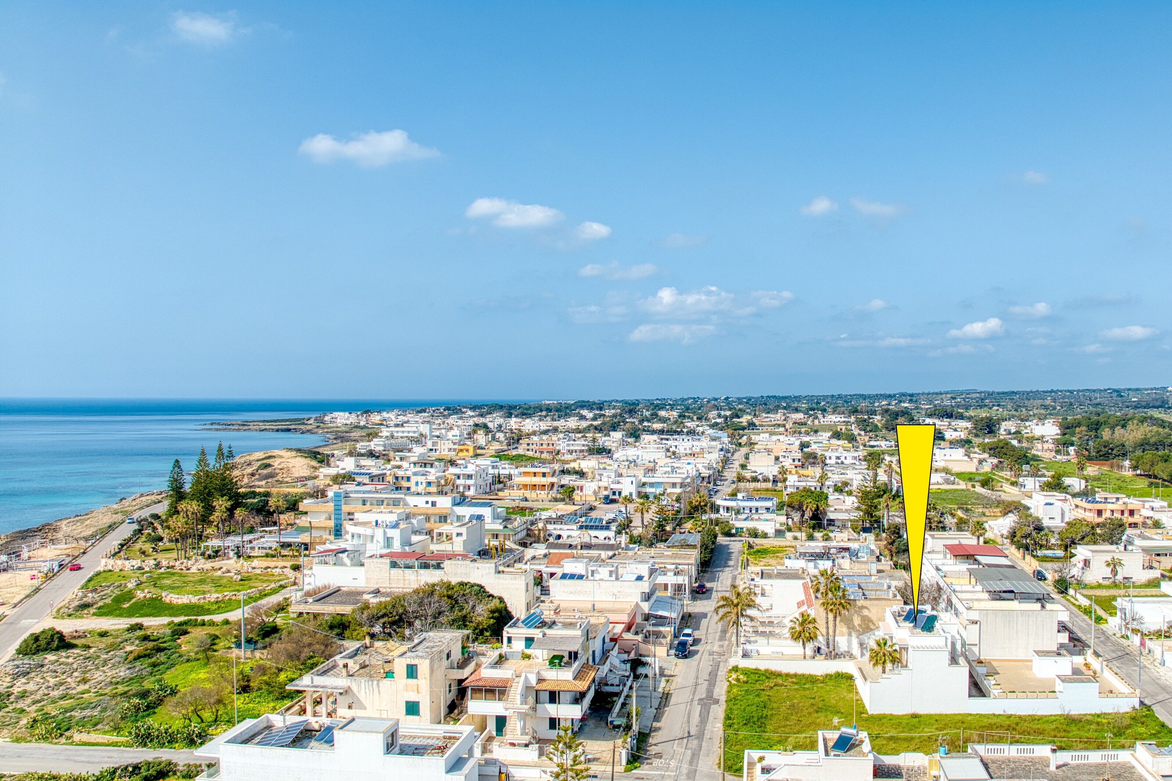 Un pueblo costero con una mezcla de edificios residenciales, un marcador amarillo destacado y vistas al mar.