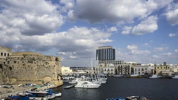 A harbor with boats, a historic stone wall, and modern buildings.