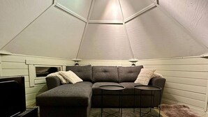Een gezellige kamer met een hoekbank, twee bijzettafeltjes en een plafondventilator.