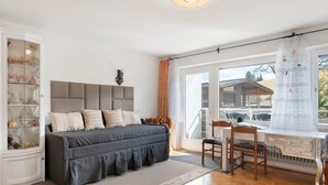 A bedroom with a bed, a desk, a chair, a radiator, and a window with curtains. - Schönwald Black Forest Homes – Apartment with Pool, Small Lake, 100 m to Ski Lift (Schönwald im Schwarzwald)