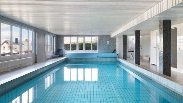 A swimming pool with a bench, large windows, and a view of the outside. - Schönwald Black Forest Homes – Apartment with Pool, Small Lake, 100 m to Ski Lift (Schönwald im Schwarzwald)
