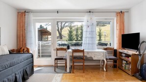 A room with a bed, a desk with chairs, a television, and a bookshelf. - Schönwald Black Forest Homes – Apartment with Pool, Small Lake, 100 m to Ski Lift (Schönwald im Schwarzwald)