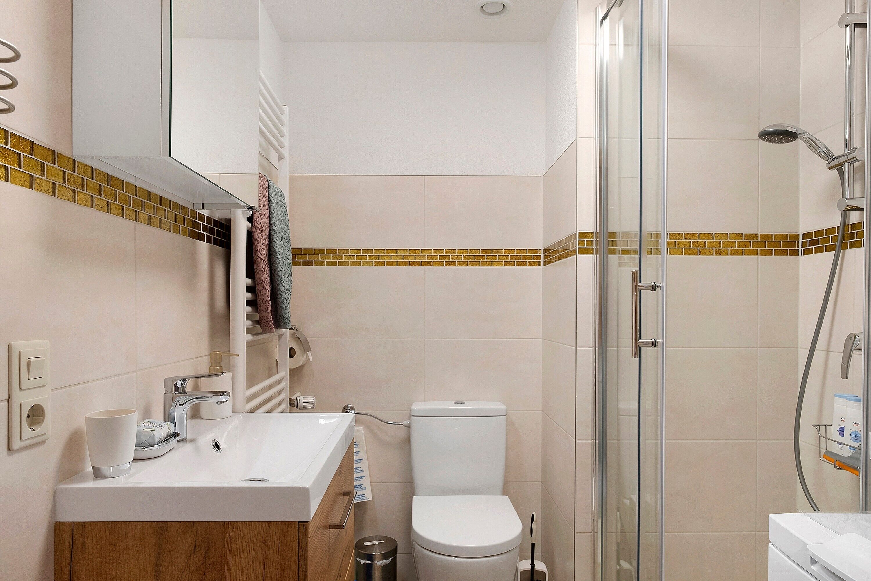 A bathroom with a white sink, toilet, and glass shower enclosure.