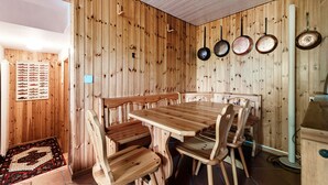 Interior de madera con una mesa y sillas de comedor, un pez exhibido en la pared y una estufa.
