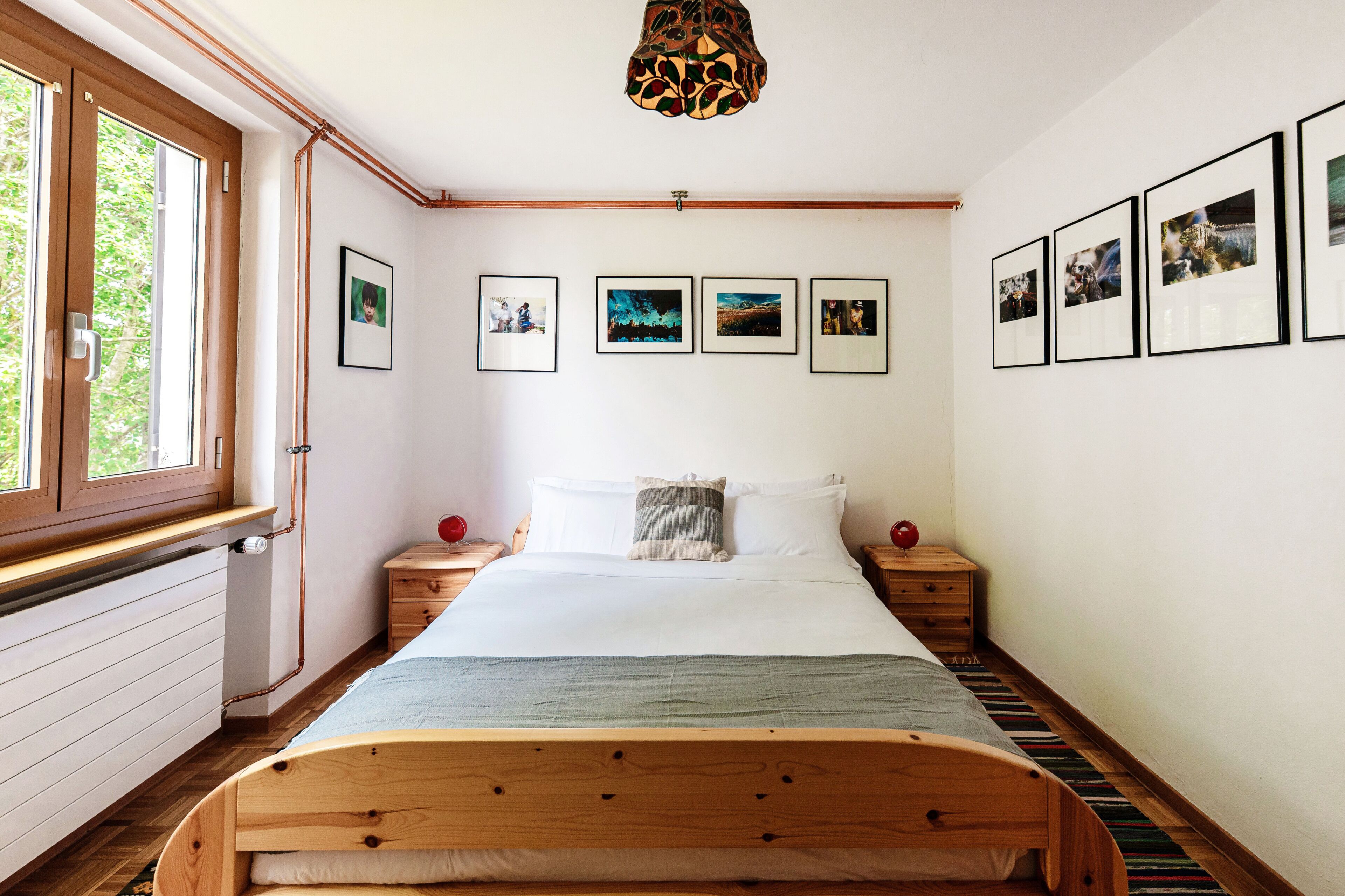 Ein Schlafzimmer mit einem hölzernen Bett, einem Fenster und gerahmten Bildern an der Wand.